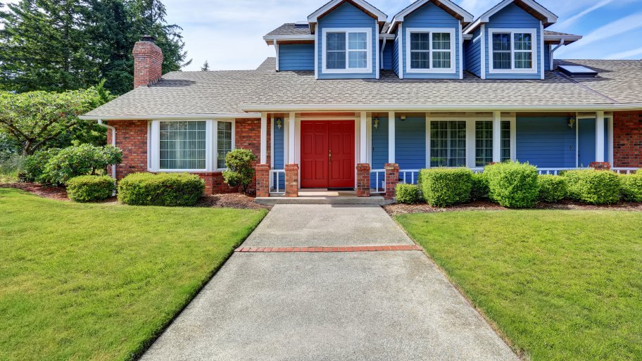 Two-story brick and blue-painted house with bold red entryway door